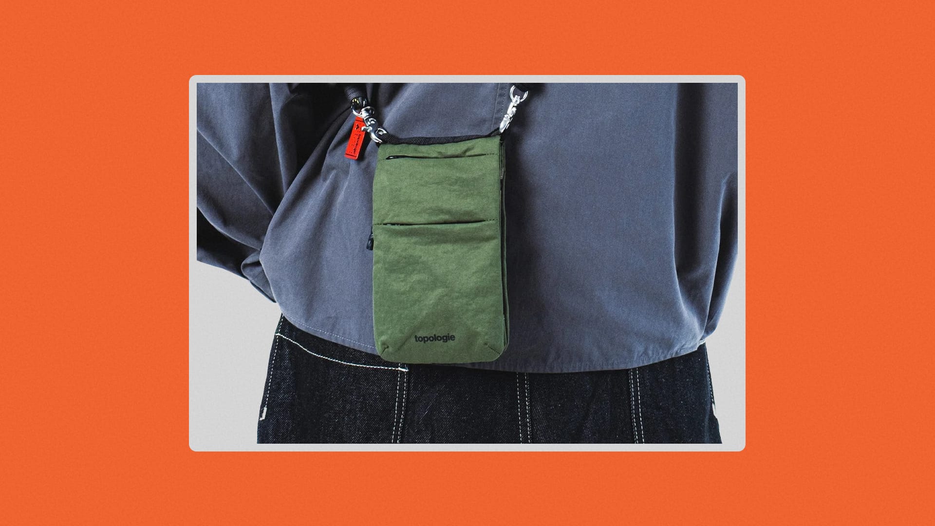 Man wearing a blue sweatshirt using a moss green phone purse.